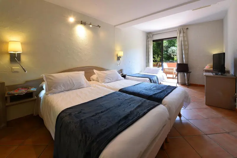 Une chambre lumineuse avec deux lits simples et une télévision.