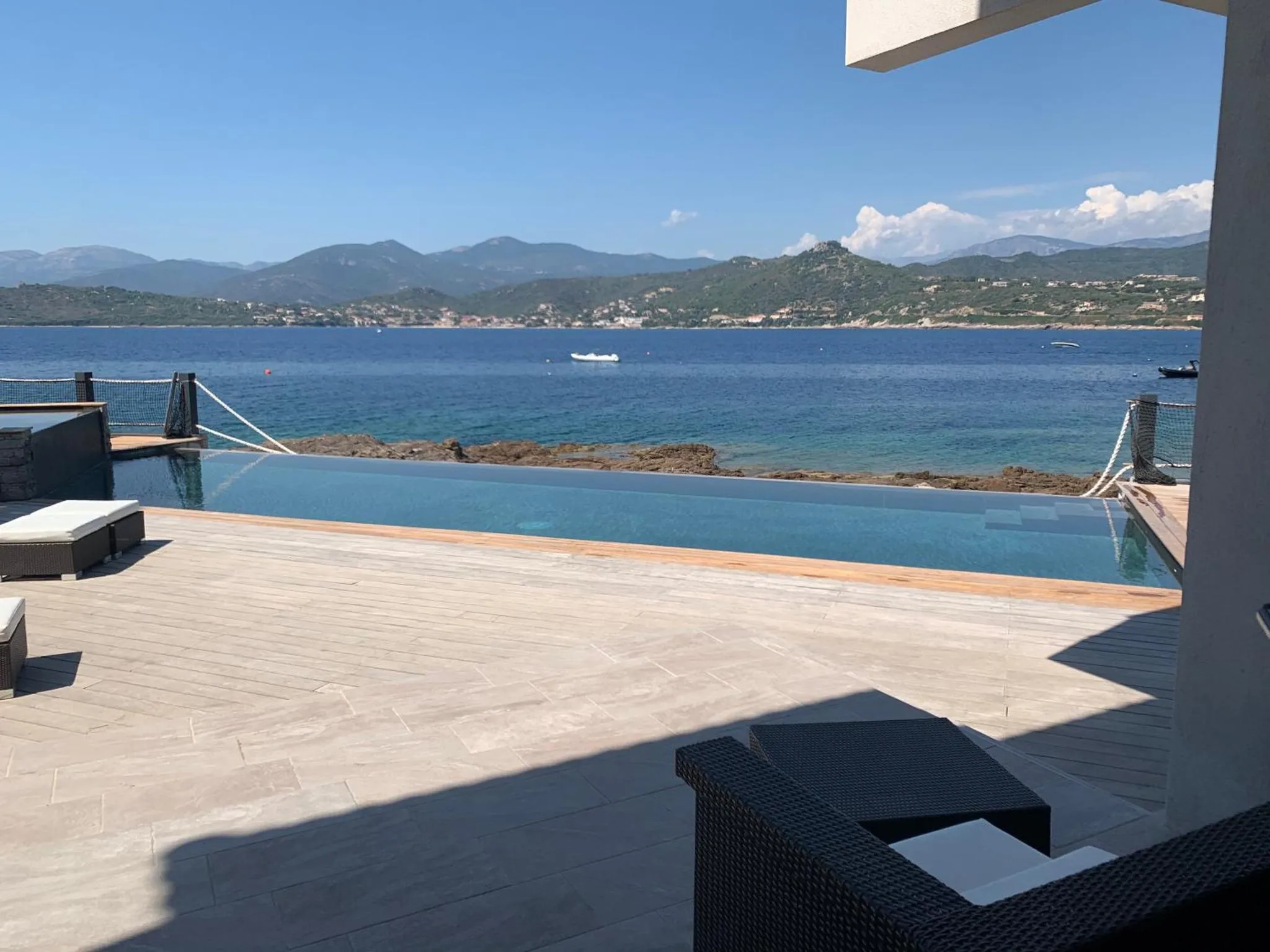 Terrasse avec piscine à débordement donnant sur la mer et les montagnes.