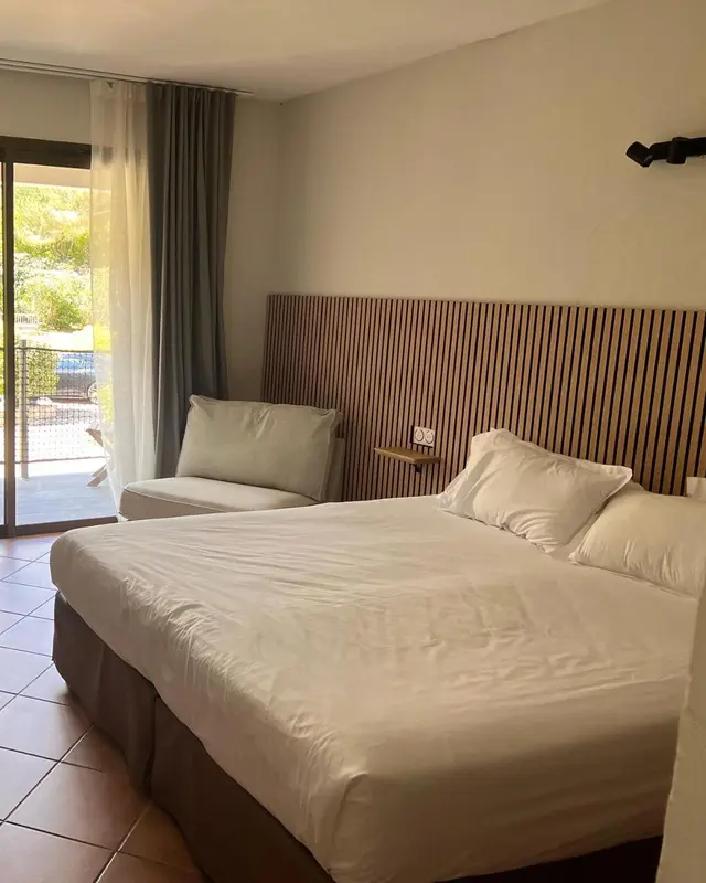 Une chambre lumineuse avec un grand lit et un coin salon.
