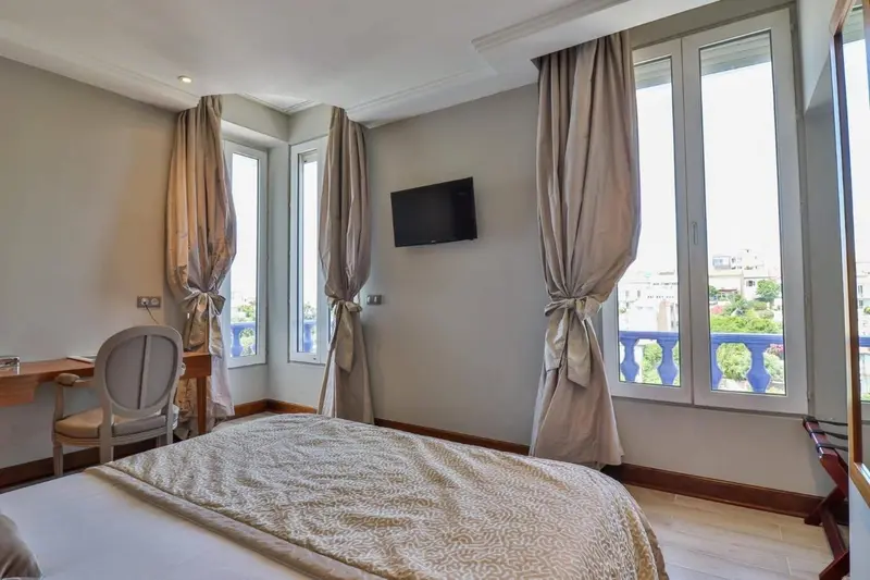 Chambre lumineuse avec un lit et un bureau près d'une fenêtre.