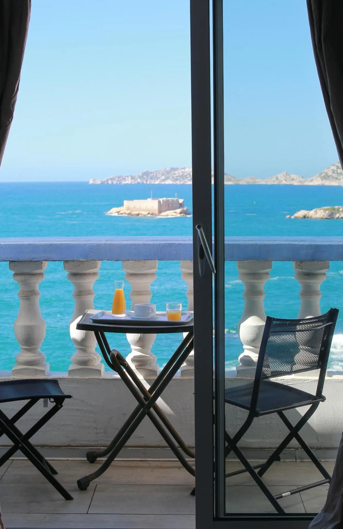 Une table avec des boissons est posée sur un balcon donnant sur la mer.
