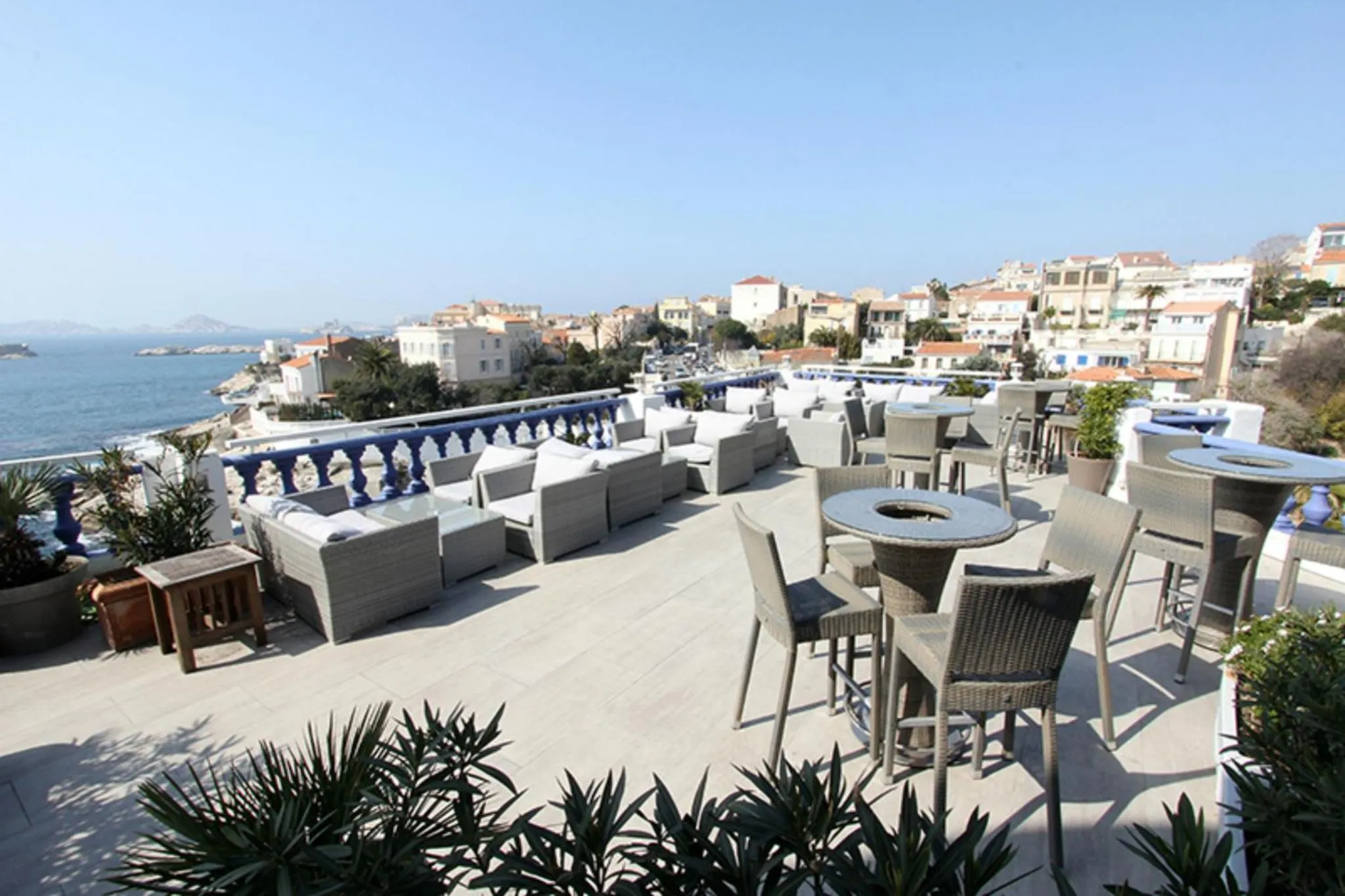 Terrasse aménagée avec des salons et des tables, vue sur la mer et la ville.