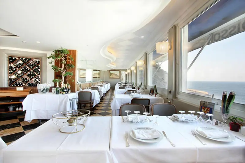 Une salle de restaurant lumineuse avec de grandes fenêtres donnant sur la mer.