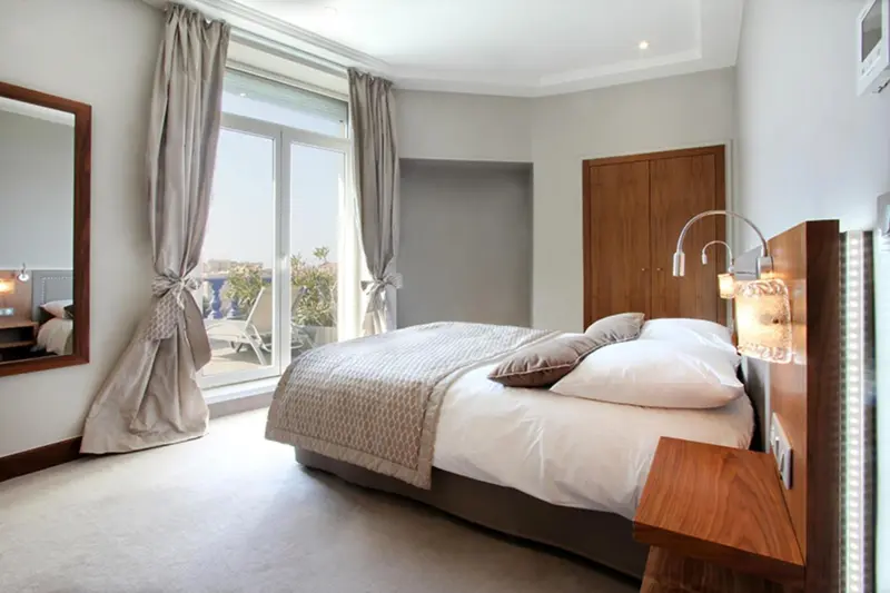 Une chambre lumineuse avec un grand lit et un accès à une terrasse.