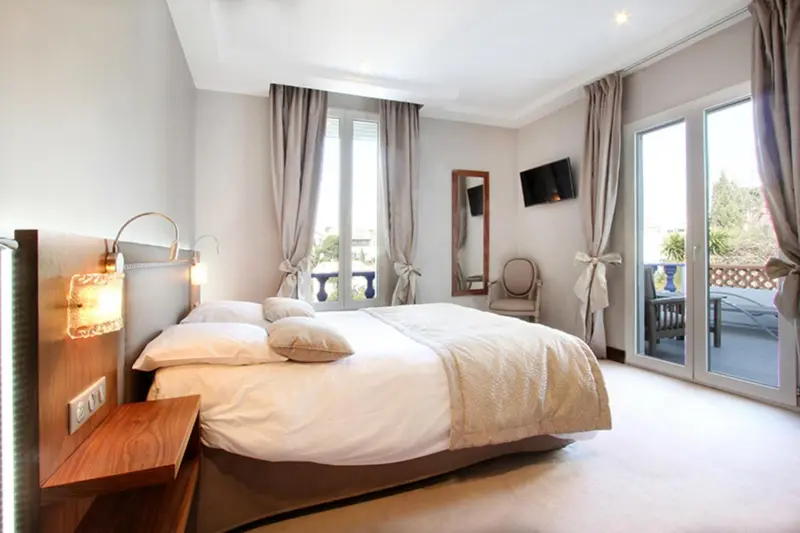 Une chambre lumineuse avec un grand lit et un accès à un balcon.