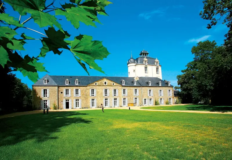 Bâtiment historique avec pelouse verdoyante et arbres.