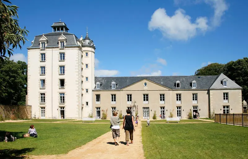 Château ancien avec pelouse verdoyante et allée centrale.
