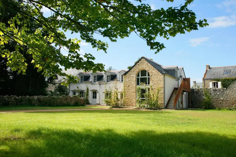 Bâtiment en pierre avec un jardin verdoyant ensoleillé.