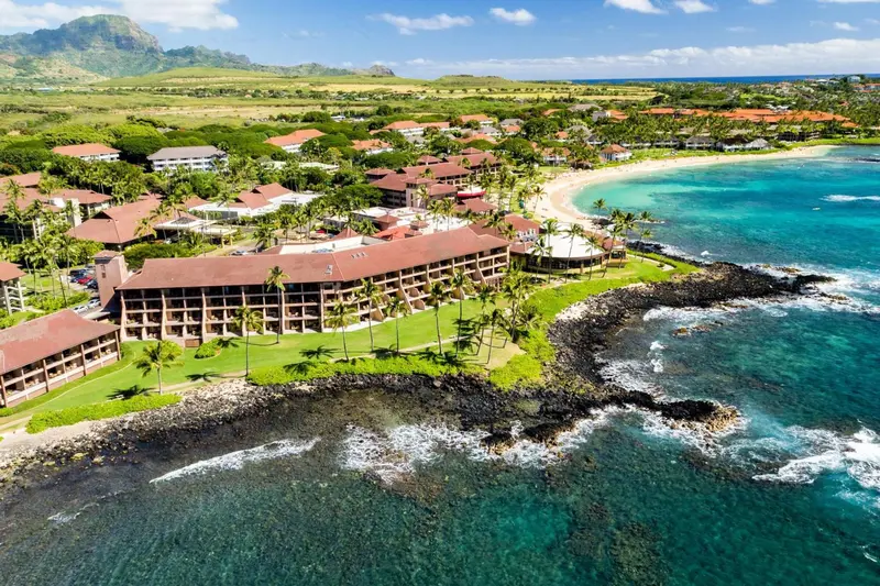 Vue aérienne d'un complexe hôtelier bordant une plage et une côte rocheuse.