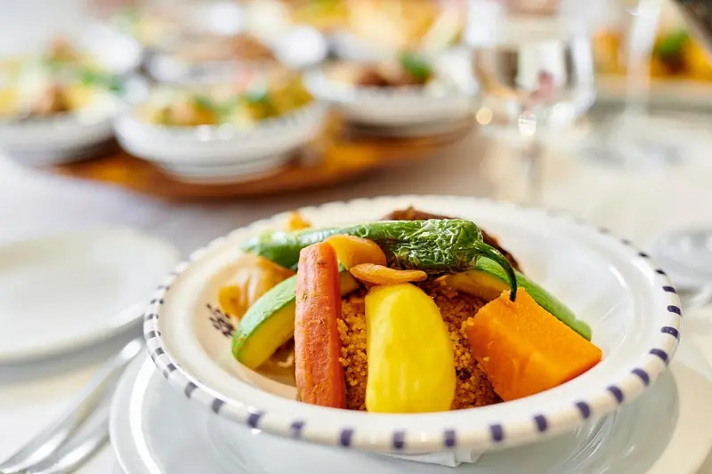 Assiettes de légumes colorés et de couscous présentés sur une table.