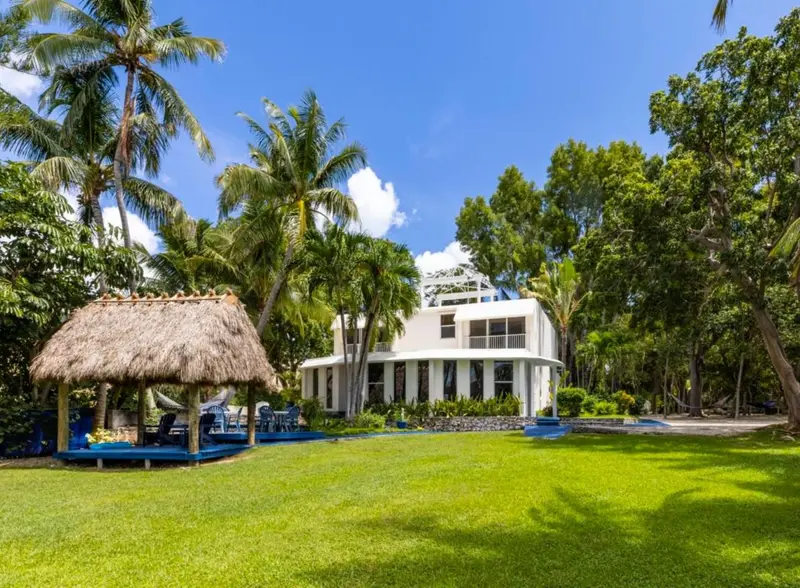 Bâtiment blanc entouré de végétation tropicale et d'une pelouse verte.