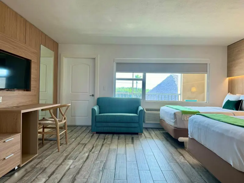 Une chambre lumineuse avec un canapé turquoise et un grand lit.