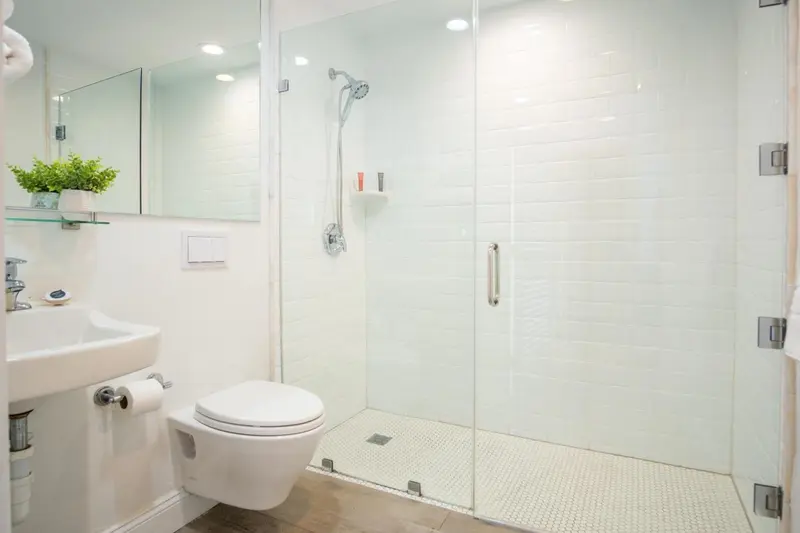 Une salle de bain claire avec douche à l'italienne et sanitaires blancs.
