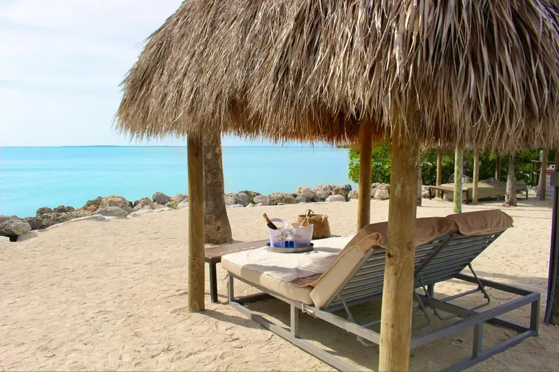 Deux transats invitent à la détente sur une plage de sable fin.