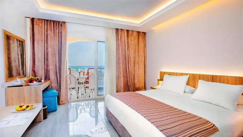 Une chambre lumineuse avec un lit double et un accès à un balcon.