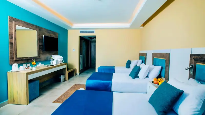 Chambre lumineuse avec deux lits simples et un coin repos.