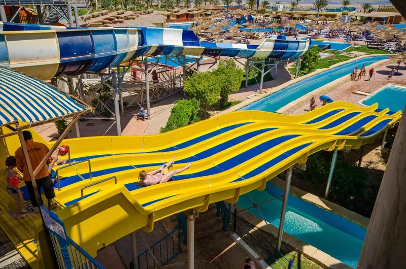 Des toboggans aquatiques colorés serpentent au-dessus d'une piscine ensoleillée.