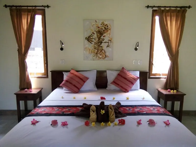 Une chambre avec un grand lit recouvert de fleurs et de coussins.