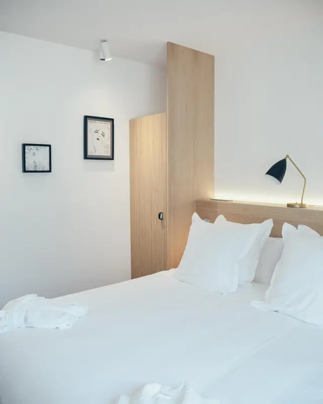 Une chambre lumineuse avec un grand lit recouvert de linge blanc.