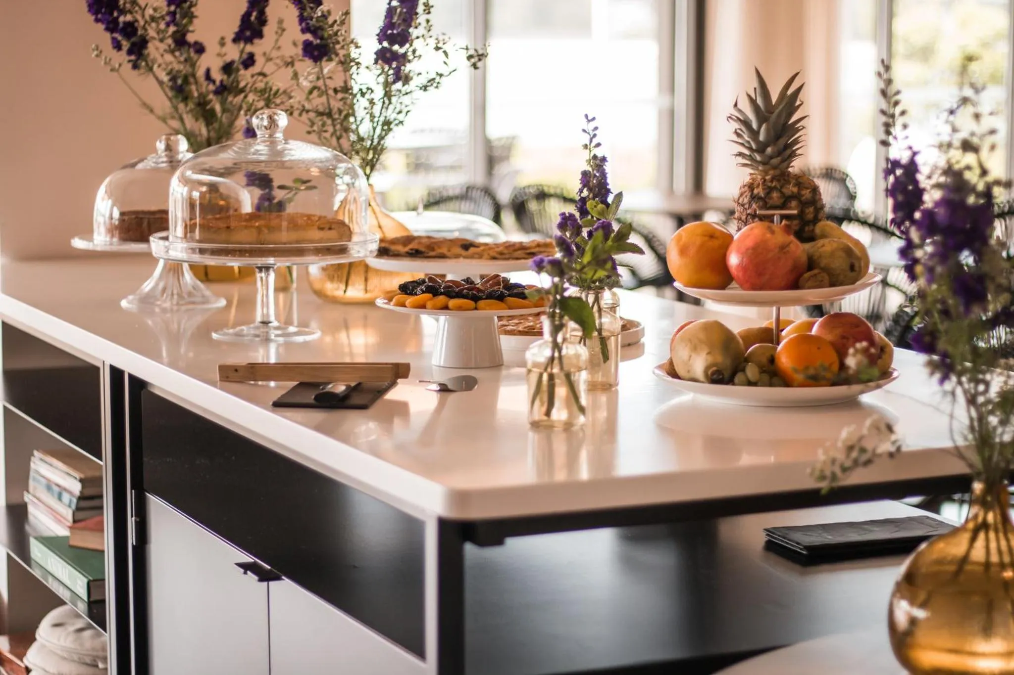 Une table garnie de pâtisseries et de fruits frais est présentée sur un comptoir blanc.