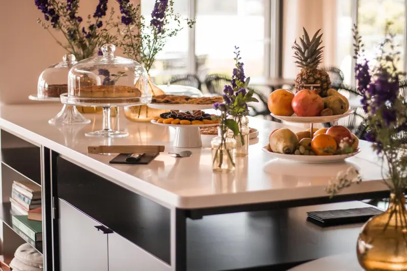 Une table garnie de pâtisseries et de fruits frais est présentée sur un comptoir blanc.