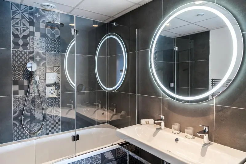 Une salle de bain moderne avec une baignoire et un grand miroir lumineux.