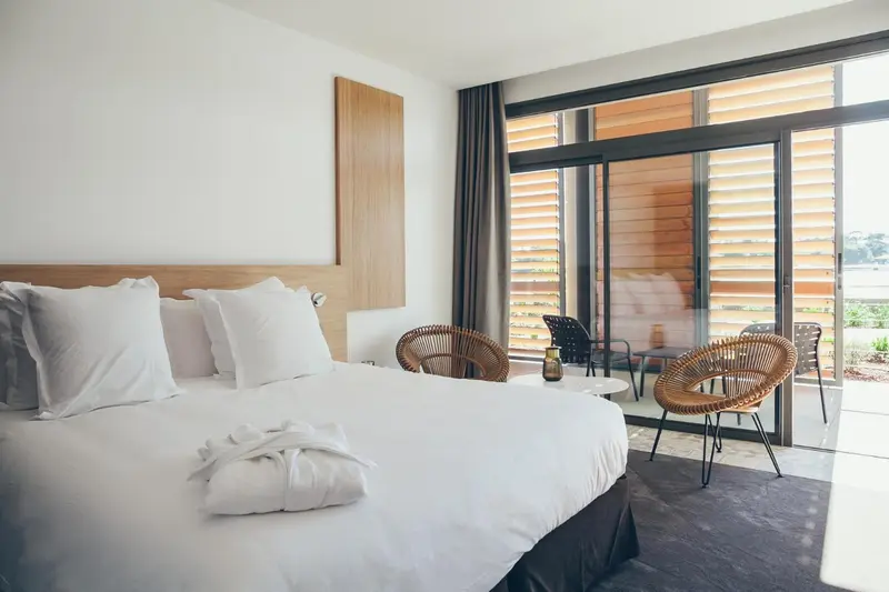 Chambre lumineuse avec un grand lit et un accès à une terrasse.