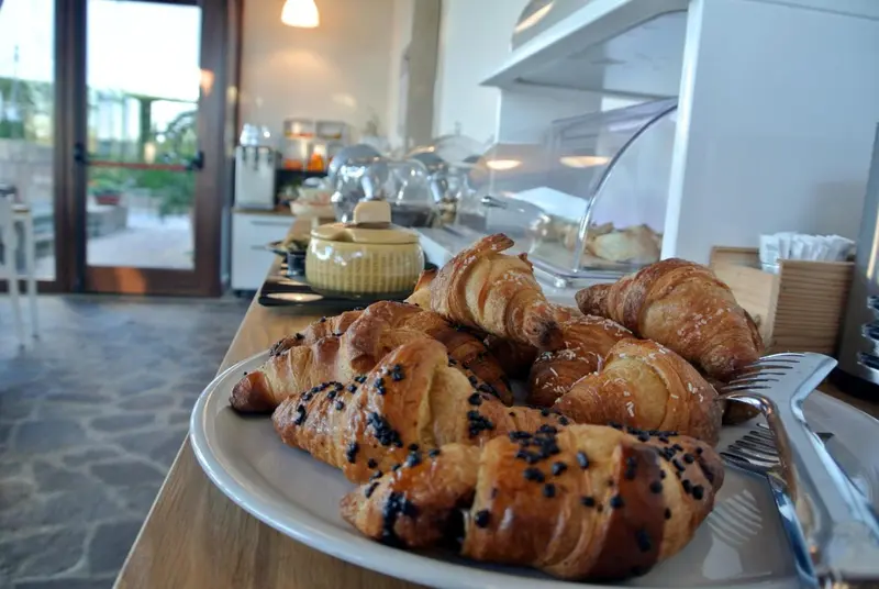 Une table garnie de viennoiseries et de pains frais est présentée dans un espace lumineux.