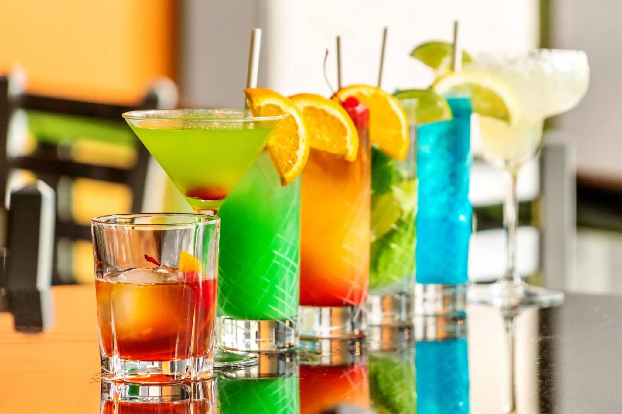 Des cocktails colorés sont présentés sur une table brillante.