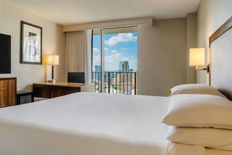 Une chambre lumineuse avec un grand lit et une vue sur la ville.