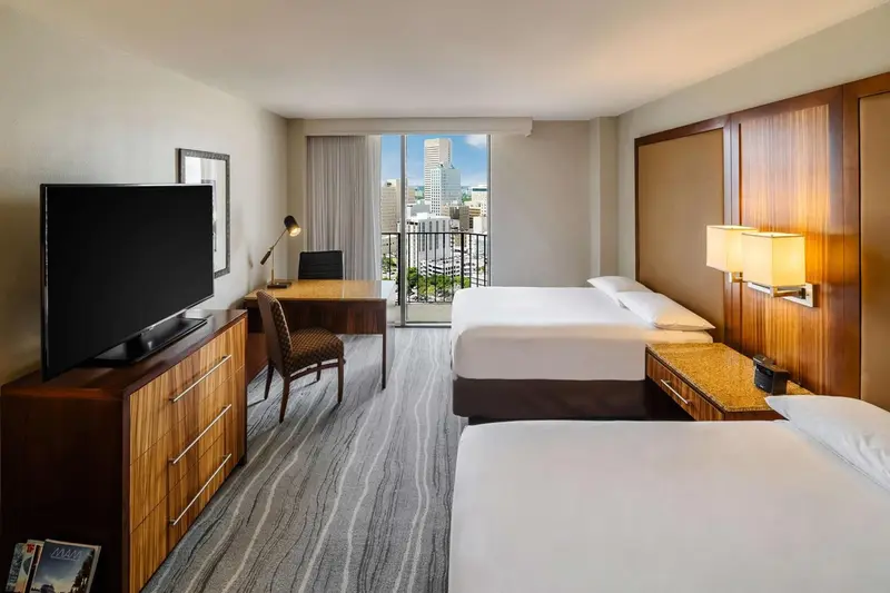 Chambre d'hôtel lumineuse avec deux lits et vue sur la ville.