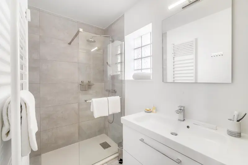 Une salle de bain moderne avec douche à l'italienne et vasque blanche.