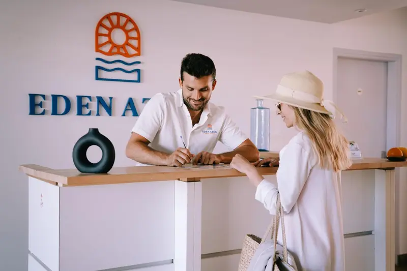 Un employé accueille une cliente à la réception d'un établissement.