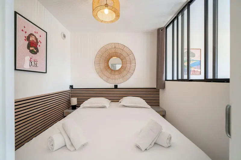 Une chambre lumineuse avec un lit double et une décoration murale.