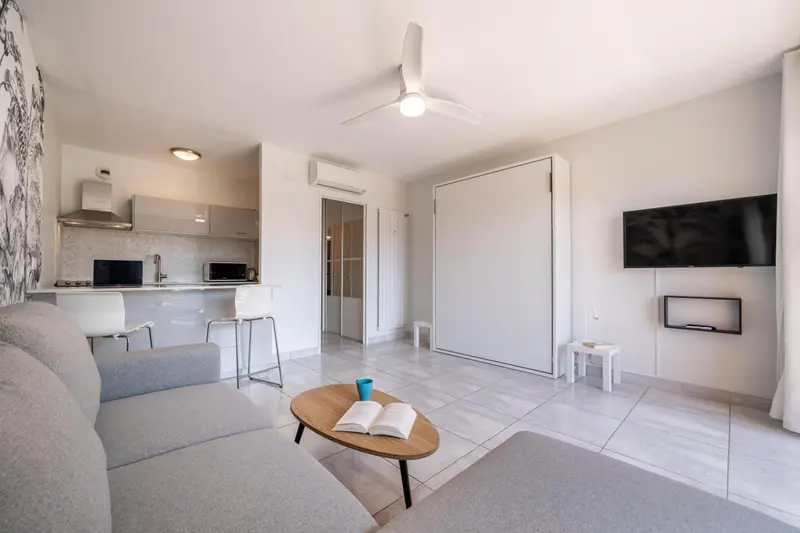 Un espace de vie lumineux avec un canapé, une table basse et une kitchenette.