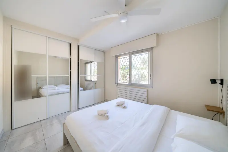 Une chambre lumineuse avec un grand lit et des armoires miroir.