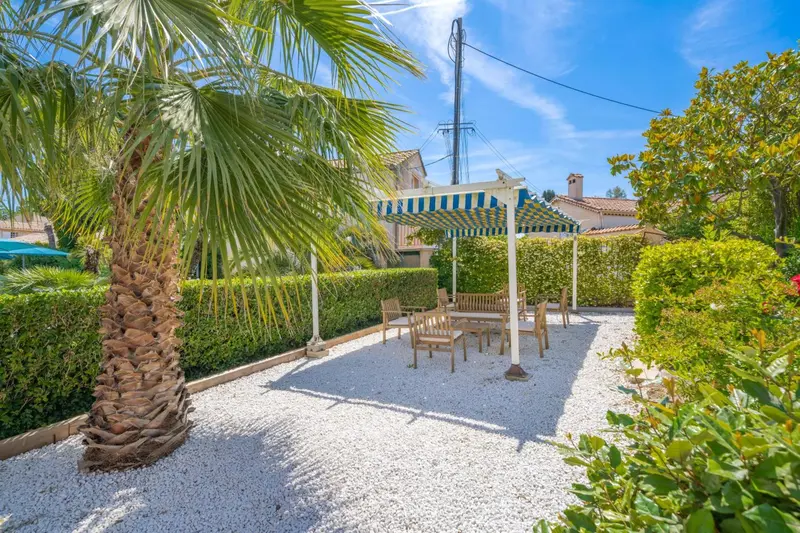 Une pergola ombrageant une table et des chaises dans un jardin soigné.