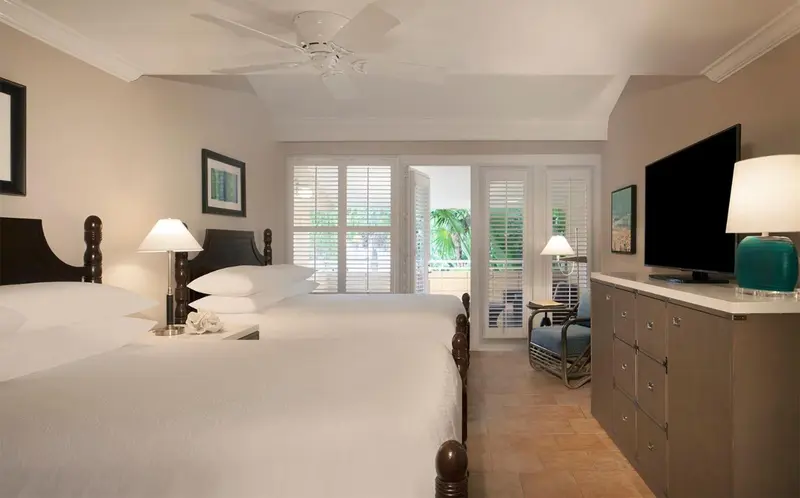 Une chambre lumineuse avec deux lits et un accès à une terrasse.
