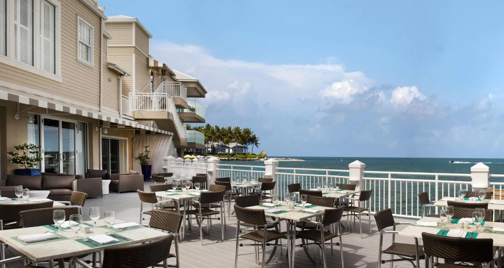 Terrasse de restaurant avec tables dressées face à la mer.
