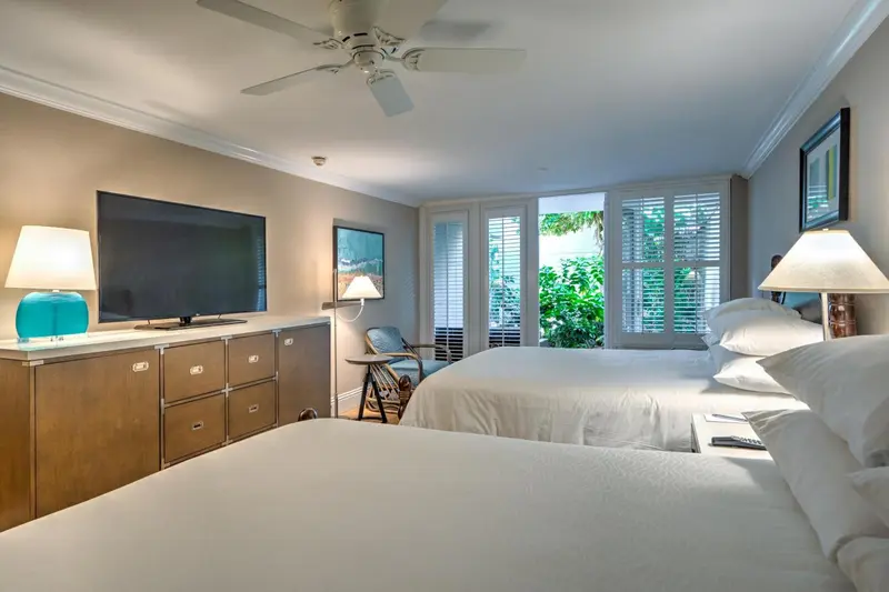 Une chambre lumineuse avec deux lits et une vue sur la végétation.