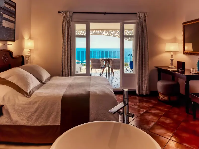 Une chambre lumineuse avec un grand lit et une vue sur la mer.