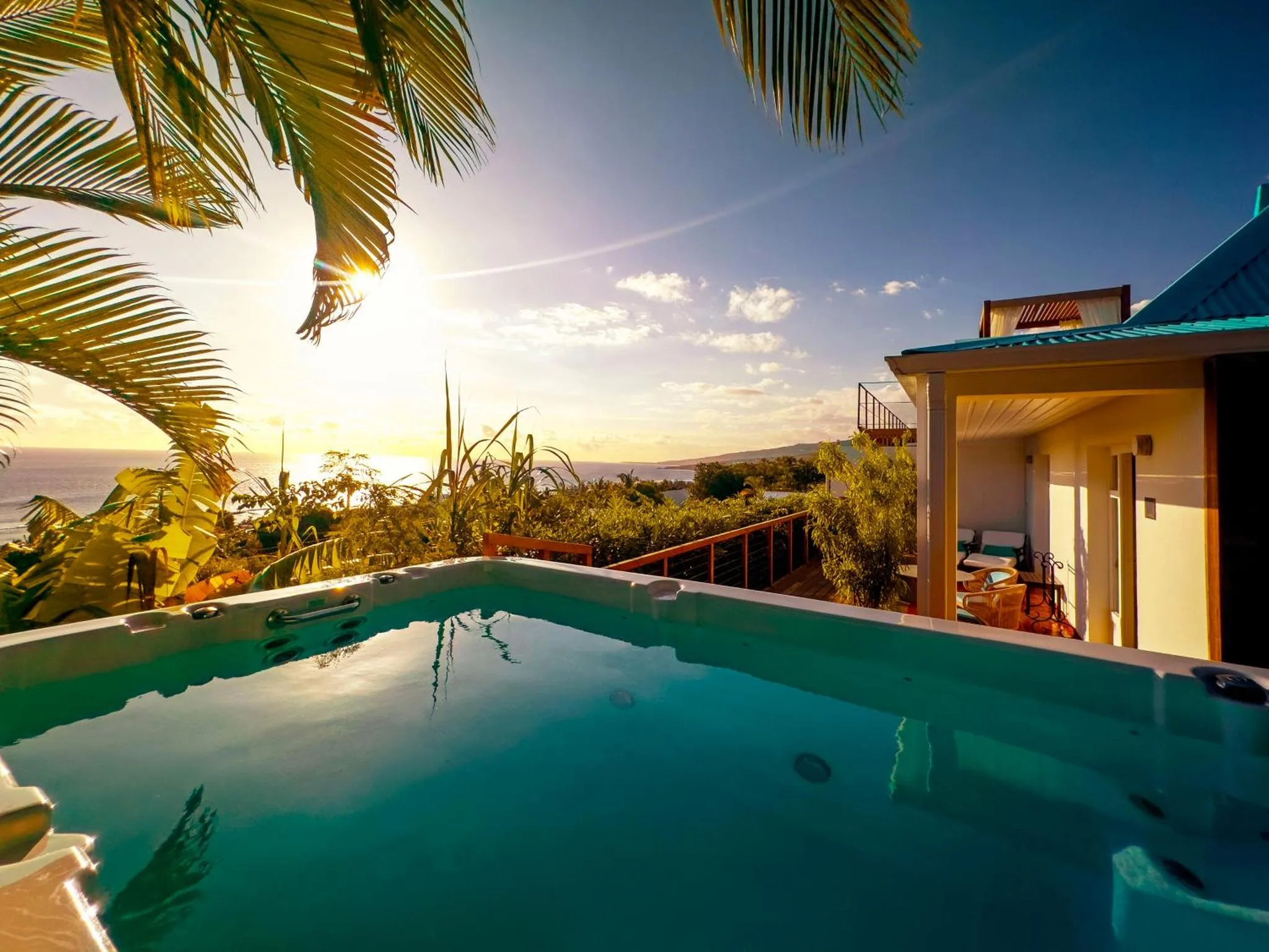 Une piscine à débordement offre une vue sur la mer et un coucher de soleil.