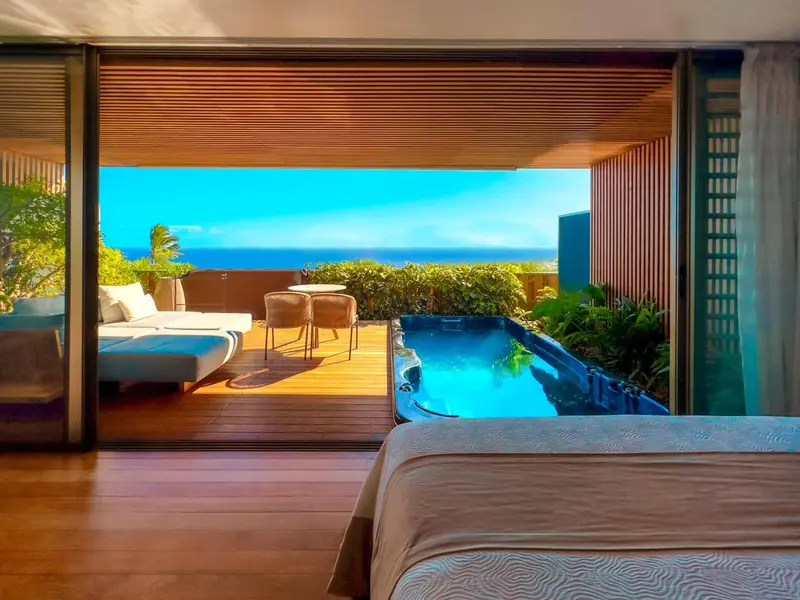 Une chambre s'ouvre sur une terrasse avec jacuzzi et vue sur la mer.