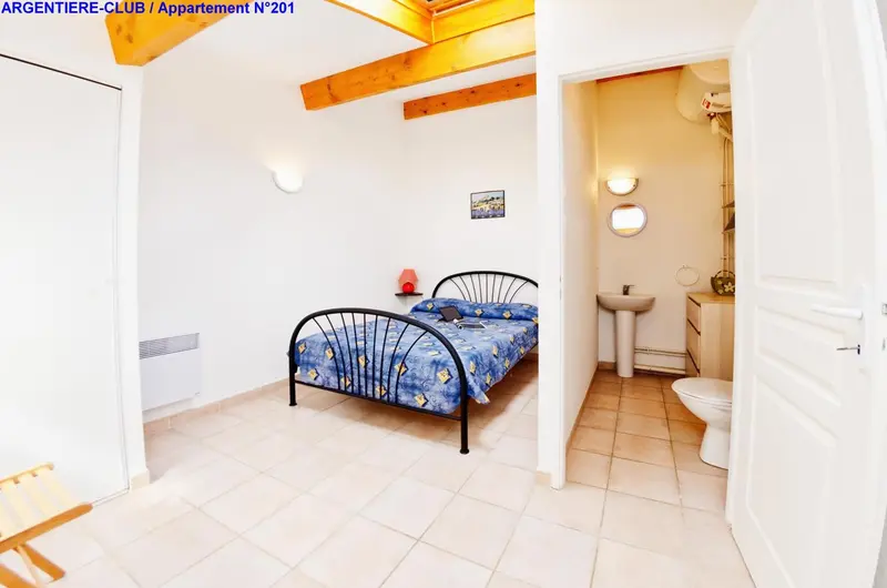 Une chambre lumineuse avec un lit à baldaquin et une salle de bain attenante.