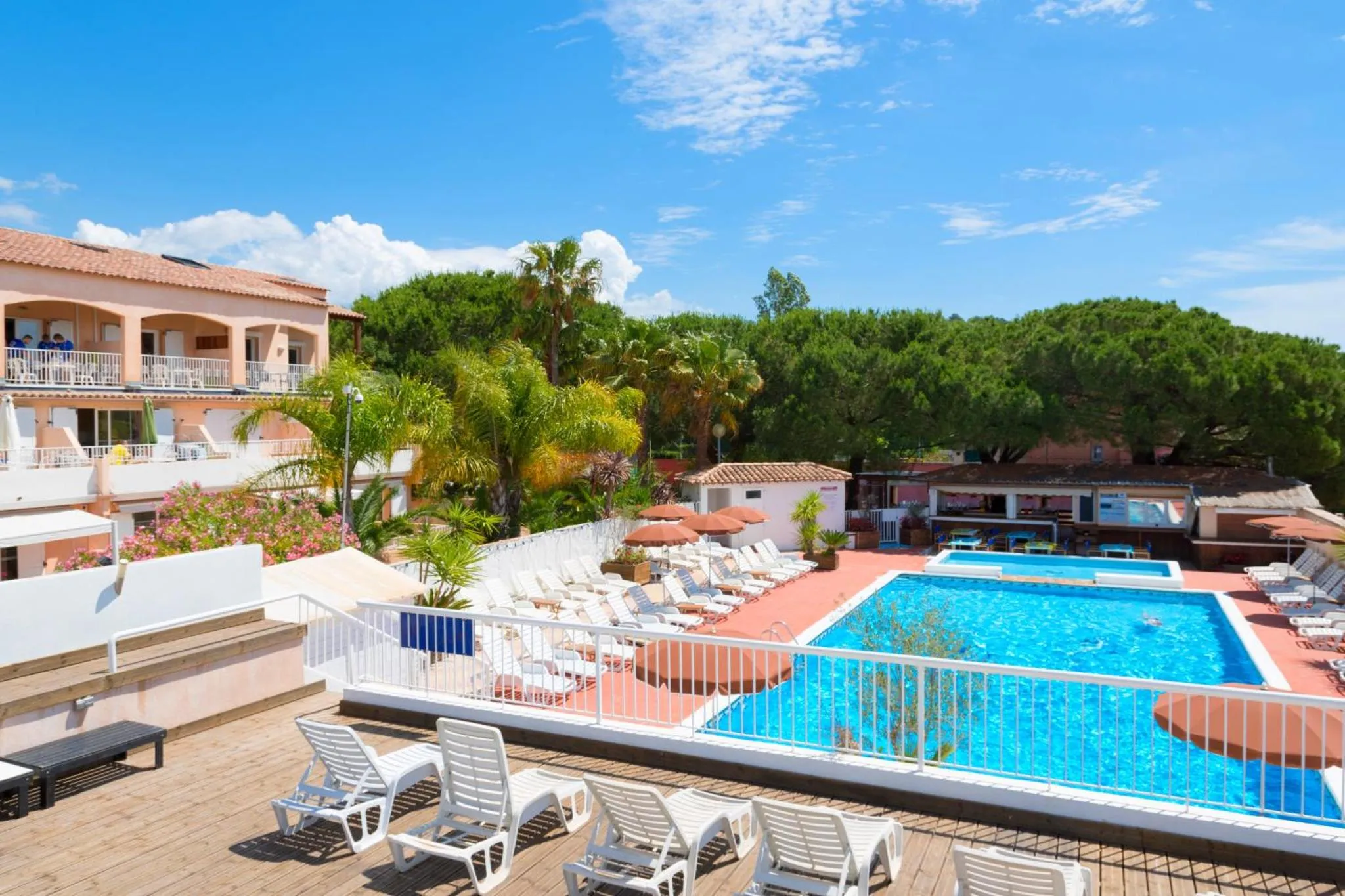 Terrasse avec transats et piscine en contrebas.