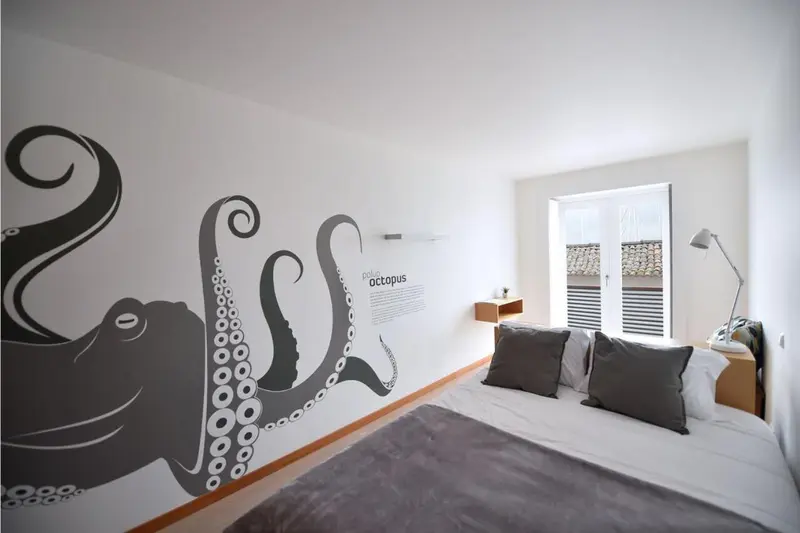 Une chambre lumineuse avec un grand lit et une décoration murale marine.