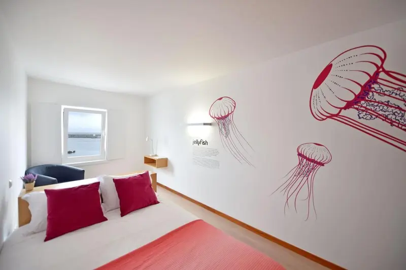Chambre lumineuse avec un lit double et une décoration murale marine.