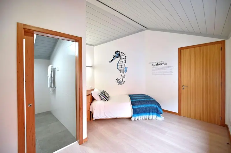 Chambre lumineuse avec un lit simple et une décoration marine.
