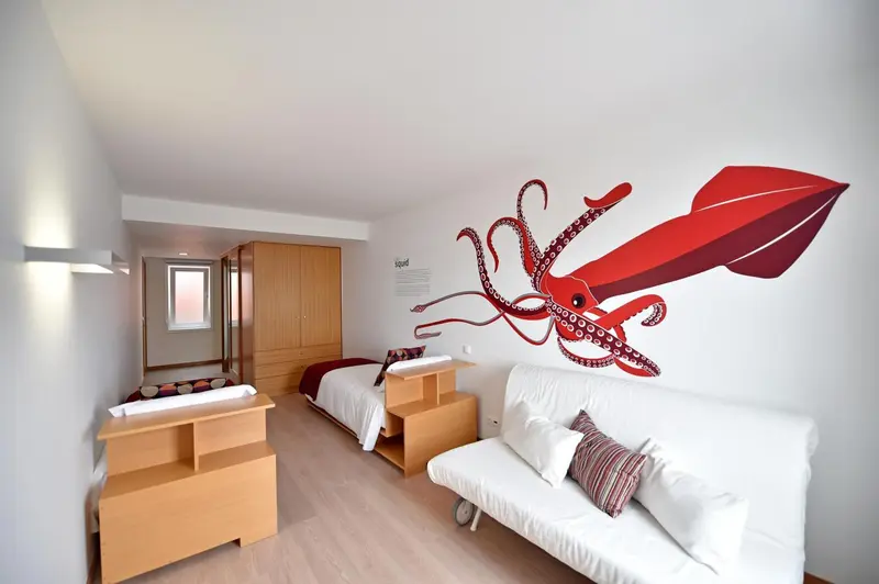 Chambre avec deux lits simples et décoration murale représentant une pieuvre rouge.