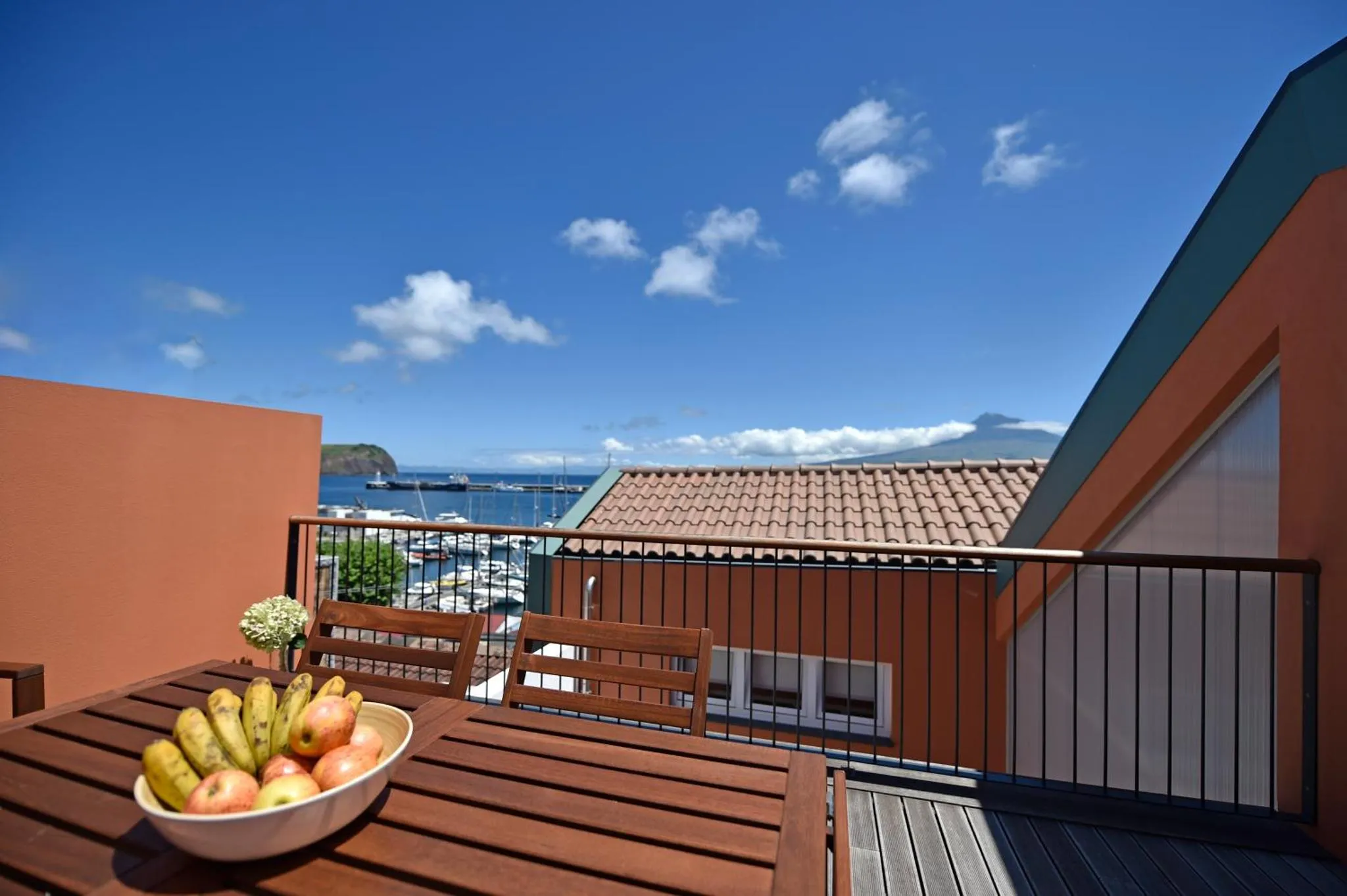Une table en bois avec des fruits est mise en scène sur une terrasse ensoleillée.